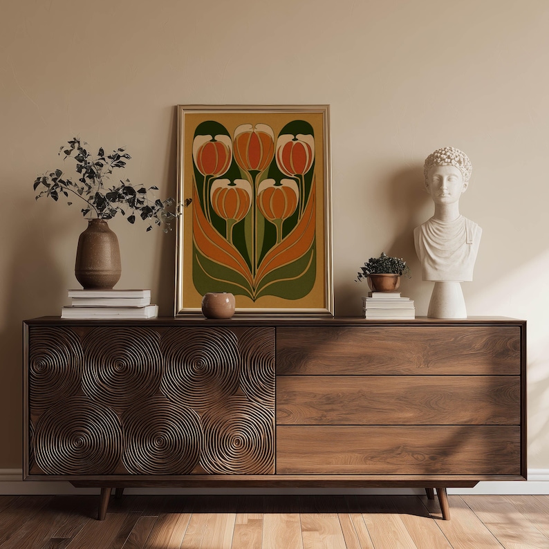 Decorative vintage tulip design in orange and deep green tones wall art print resting on a mid century sideboard styled with sculptural decor and books.