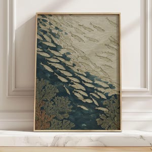 May include: A framed art print featuring a school of fish swimming in a dark blue ocean. The artwork has a vintage aesthetic, with the fish rendered in shades of white and gray. Coral-like structures are visible at the bottom of the print.