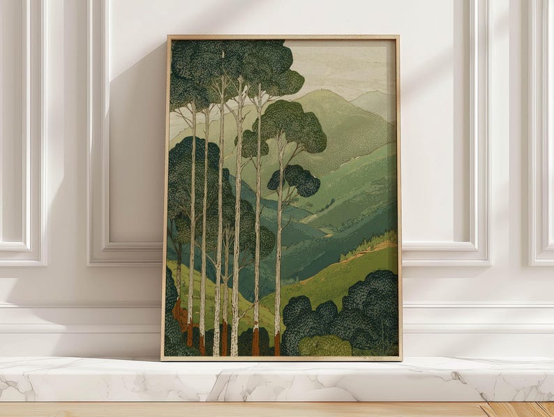 Tall trees and layered green hills in a vintage-style, calm wall art print, shown framed on a marble ledge in sunlit close-up.