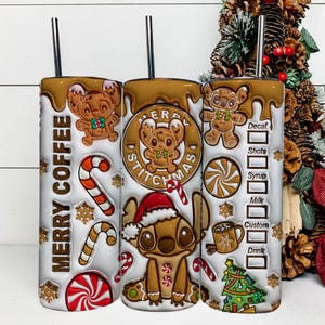 May include: Three stainless steel tumblers with a Christmas theme. The tumblers feature a gingerbread Stitch design, candy canes, snowflakes, and the words "Merry Coffee" and "Merry Stitchmas". Each tumbler has a silver straw.
