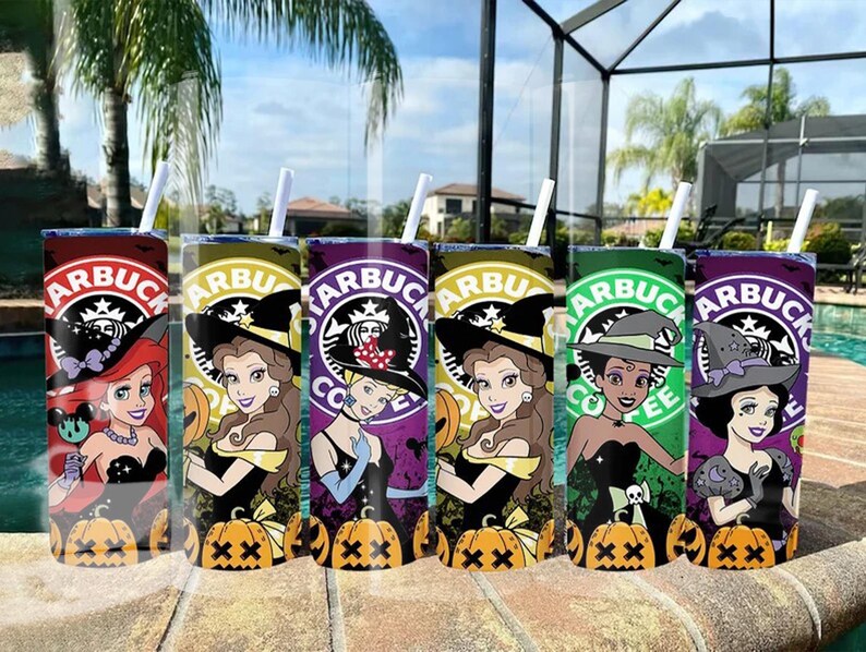 May include: Six Starbucks-themed tumblers featuring Disney princesses in Halloween witch costumes. Each tumbler has a different color scheme, including red, yellow, purple, green, and orange, with a pumpkin and witch hat design. The tumblers have white straws.
