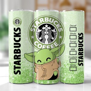 May include: A green and white Starbucks tumbler featuring the Starbucks logo, the text "STARBUCKS", and a cartoon image of a green alien character. The tumbler has a glittery design and a drink customization chart.