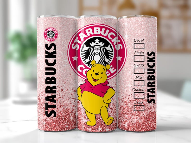 May include: A pink glitter Starbucks tumbler featuring Winnie the Pooh. The tumbler has the Starbucks logo and text. The design includes a drink customization chart. The tumbler is cylindrical and has a pink glitter gradient.