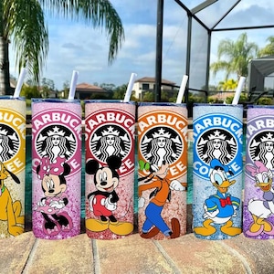 May include: Six glitter-covered tumblers with Disney character designs. Each tumbler features a Starbucks logo and a different character: Pluto, Minnie Mouse, Mickey Mouse, Goofy, Donald Duck, and Daisy Duck. Each has a straw.