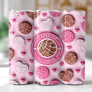 May include: A pink tumbler featuring a repeating pattern of conchas, hearts, and a central emblem. The emblem reads "Cafecito y Chisme" in a circular design. The conchas are in shades of brown, pink, and white.