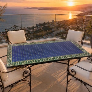 Puede incluir: Una mesa de comedor rectangular para exteriores con una superficie de azulejos azules y verdes con un patrón geométrico, sostenida por un marco de hierro forjado negro, acompañada de cuatro sillas de hierro forjado negro a juego con cojines de color blanco roto.