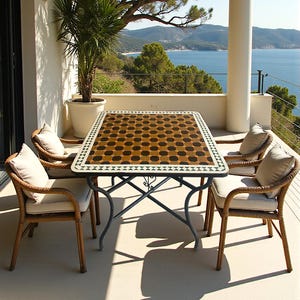 May include: Patio furniture set comprising a rectangular table and four chairs. The table features a mosaic tile top with a brown and black design. The chairs are woven wicker with cream cushions. The set is on a patio with a view of the sea.