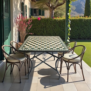May include: Outdoor dining set featuring a rectangular table with a green and white checkered tile top. The table is supported by a dark metal frame. Four chairs with curved backs and cream-colored cushions surround the table. The scene is set on a tiled patio.