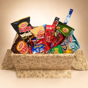 Peut inclure: Un panier cadeau débordant de divers snacks, notamment des chips, des barres chocolatées et des bonbons. Le panier est doublé de papier à motifs floraux. Plusieurs paquets ont du texte hébreu et des couleurs vives.
