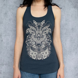 May include: A dark blue tank top with a white floral and moth design. The design features a large moth with intricate wings and a symmetrical arrangement of flowers and leaves.