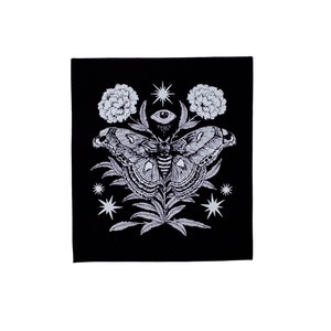 May include: Black and white illustration of a moth with a large eye in the centre, surrounded by flowers and stars.