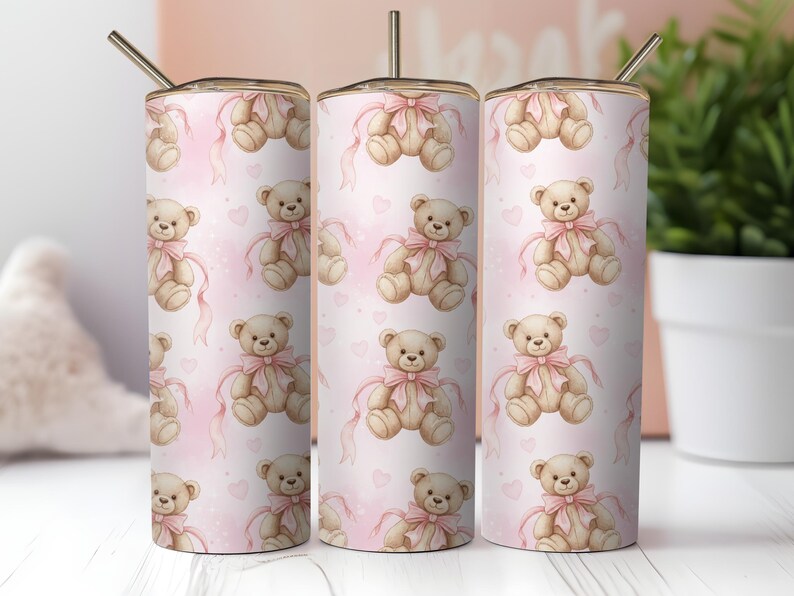 May include: Three 20 oz. stainless steel tumblers with a repeating pattern of watercolor teddy bears wearing pink bows on a pink background with hearts. Each tumbler has a gold-colored straw.