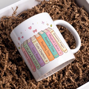 May include: A set of three ceramic mugs with a speckled, matte finish. Each mug features a different color: light blue, cream, and gray. The mugs have a simple, modern design with a rounded shape and a comfortable handle.