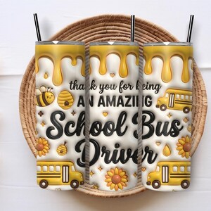 Op de afbeelding: Drie witte bekers met zwarte rietjes, met een geel honingthema-ontwerp. Het ontwerp omvat een bij, een schoolbus en de tekst "thank you for being an AMAZING School Bus Driver."