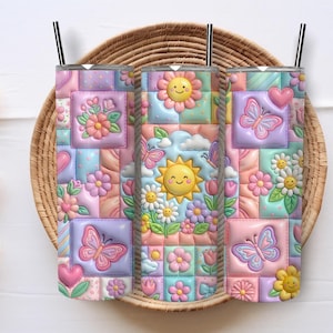 Op de afbeelding: Een cilindervormige beker met een kleurrijk patchworkontwerp met reliëfachtige afbeeldingen van lachende zonnen, roze en blauwe vlinders, diverse bloemen en hartjes in pasteltinten van roze, blauw, geel en paars, afgewerkt met een zwart rietje.