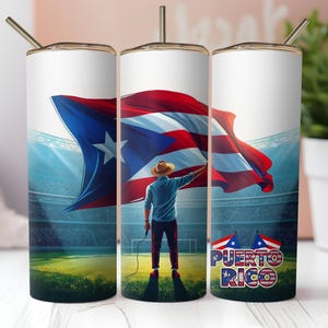 May include: A white tumbler with a gold rim and straw features a vibrant illustration of the Puerto Rican flag waving in a stadium. A person in a hat and blue shirt holds the flag. The words "Puerto Rico" are displayed below.