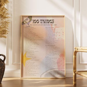 May include: A framed print with the text "100 THINGS WE SHOULD DO BEFORE WE DIE" in a retro font. The print has a soft, watercolor-like background with a list of items. A decorative vase with dried plants is on the left.