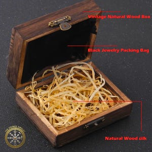 Puede incluir: Una caja de madera natural vintage, abierta para revelar una bolsa de embalaje de joyer&iacute;a negra y seda de madera natural. La caja es rectangular con una tapa con bisagras y un cierre de metal. La caja es de madera marr&oacute;n oscuro.