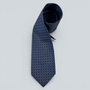 Pode incluir: Uma gravata azul-marinho com um padrão repetitivo de pontos pequenos, escuros e espaçados uniformemente. A gravata está enrolada no topo, mostrando a textura do tecido e a extremidade pontiaguda na parte inferior. O design é consistente e uniforme.