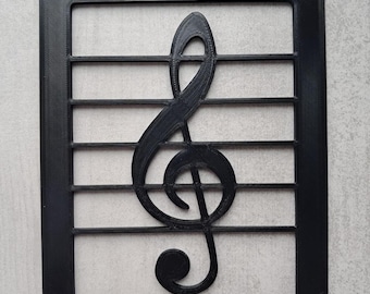 May include: A black, 3D-printed treble clef music symbol within a rectangular frame with horizontal lines. The design is a decorative piece, suitable for music enthusiasts or as wall art. The clef is a prominent feature.