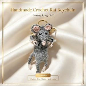 Könnte beinhalten: Ein handgefertigter Häkel-Ratten-Schlüsselanhänger mit flauschigem grauem Körper, rosa Innenohren, rosa Nase und schwarzen Perlenaugen. Die Ratte ist an einem goldfarbenen Metallring befestigt. Der Text lautet: Handmade Crochet Rat Keychain.