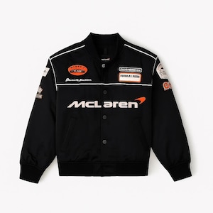 Puede incluir: Chaqueta bomber negra con detalles blancos y varios parches. La chaqueta presenta el logotipo de McLaren en blanco en el pecho. Los parches incluyen el texto "Street Dreams" y "Formula 1 Racing".