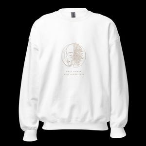 Peut inclure: Sweat-shirt blanc avec un motif doré. Le motif représente un visage humain et un motif de circuit imprimé dans un cercle. Le texte "HALF HUMAN HALF ALGORITHM" est en dessous. Vêtement unisexe.