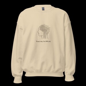 Peut inclure: Un sweat-shirt crème avec un design minimaliste. Un profil de tête avec un design de circuit imprimé remplaçant le cerveau est imprimé sur le devant. En dessous du graphique, le texte indique : "Trust me, I'm 99% AI."