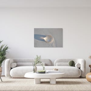 May include: A clear glass sphere casting a long shadow on a light-colored surface. The sphere appears to be reflecting light, creating a bright spot. The image is a close-up shot, emphasizing the texture and form of the glass.