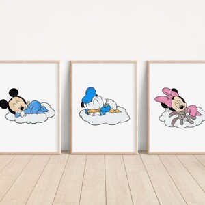 May include: Three framed prints featuring cartoon characters. Mickey Mouse in blue pajamas, Donald Duck in a blue sailor suit, and Minnie Mouse in a pink dress, all sleeping on clouds. The prints are in light wood frames.