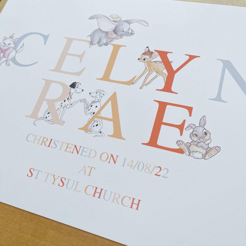 K&ouml;nnte beinhalten: Eine wei&szlig;e Karte mit dem Namen "CELYN RAE" in orangefarbenen und grauen Buchstaben, verziert mit Zeichentrickfiguren wie Dumbo, Bambi und Thumper. Die Karte enth&auml;lt auch den Text "CHRISTENED ON 14/08/22 AT ST TYSUL CHURCH."