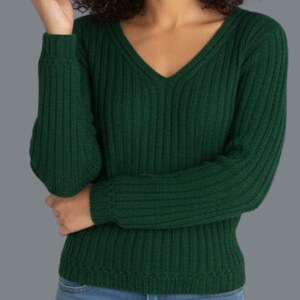 May include: A dark green ribbed knit sweater with a V-neck. The long-sleeved sweater is made of a soft material and is a solid color. The model is wearing blue jeans.