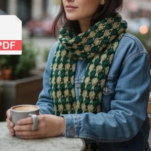 May include: A green and tan patterned scarf is draped around the neck of a person wearing a denim jacket. The person is holding a gray mug of coffee. A PDF icon is in the upper left corner.