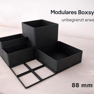 Könnte beinhalten: Ein Set aus drei Keramikbechern mit gesprenkelter, matter Oberfläche. Die Becher sind in Creme-, Hellbraun- und Dunkelbrauntönen gehalten. Jeder Becher hat ein schlichtes, minimalistisches Design.