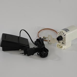 Pode incluir: Kit de motor para máquina de costura, com pedal preto, motor branco com botão preto, correia castanha e cabo de alimentação. Os componentes estão dispostos sobre uma superfície branca, prontos para instalação ou reparo.