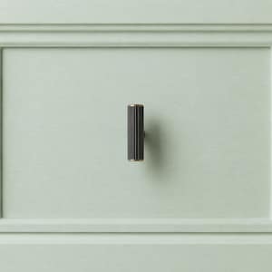 May include: A dark bronze cabinet knob with vertical ridges and gold accents. The knob is mounted on a light green cabinet door. The hardware adds a touch of elegance to furniture.