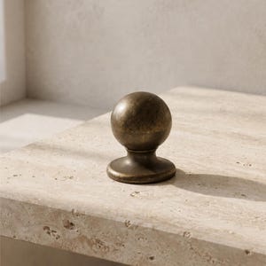 May include: A spherical cabinet knob with a dark, weathered bronze finish. The knob features a smooth, rounded top section that transitions into a flared, circular base, providing a solid and functional grip for furniture or cabinetry doors.