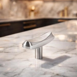 May include: A brushed nickel cabinet pull with a curved handle and a cylindrical base. The hardware is designed for a modern kitchen or bathroom. The pull is shown on a white marble countertop.