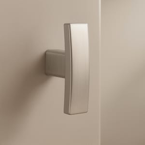 May include: A brushed nickel cabinet pull with a rectangular, curved handle. The handle is mounted on a square base, and the hardware is attached to a neutral-colored cabinet door.
