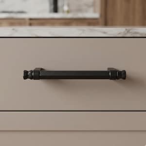 May include: A black cabinet pull with a geometric design. The rectangular bar is flanked by decorative end pieces. The hardware is mounted on a light beige cabinet door. This modern pull is suitable for kitchen or bathroom cabinets.
