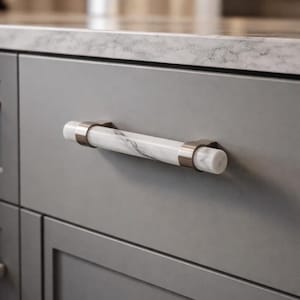 May include: A gray cabinet drawer with a marble and metal handle. The handle is cylindrical with a white marble center and metal end caps. The cabinet has a marble countertop.