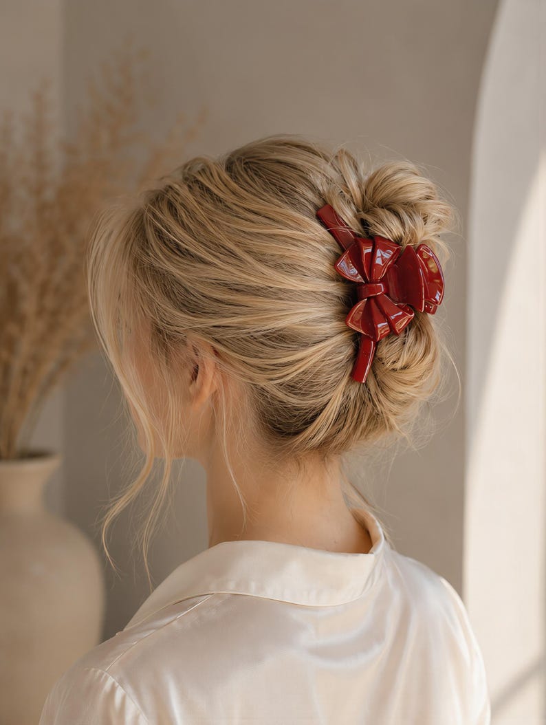 Pu&ograve; includere: Un fermaglio per capelli a molla di colore rosso scuro lucido con un design a fiocco in rilievo sulla superficie esterna. L'accessorio &egrave; dotato di denti incastrati per fissare i capelli, caratterizzato da una finitura liscia e riflettente e una forma strutturata.