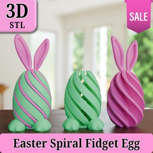 May include: Three Easter-themed spiral fidget eggs in green and pink. The eggs have bunny ears and feet. One egg is open, and the others have a striped design. The image includes the text "3D STL" and "SALE". The bottom of the image reads "Easter Spiral Fidget Egg".