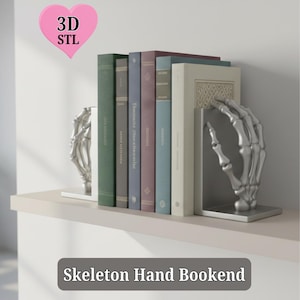 May include: Silver skeleton hand bookends holding a row of books on a white shelf. The books have various colors and sizes. The text "Skeleton Hand Bookend" is at the bottom of the image, and a pink heart with "3D STL" is in the upper left corner.