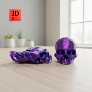 Op de afbeelding: Twee metallic paarse schedelsculpturen. Eén is een complete schedel en de andere is een geconstrueerde schedel. De sculpturen staan op een lichtgekleurd houten oppervlak. Een rood vierkant met de tekst "3D STL" staat op de achtergrond.