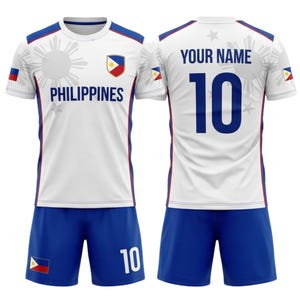 May include: A white soccer uniform with blue shorts. The jersey features the word "PHILIPPINES" and a crest. The number "10" is on the shorts and jersey. The back of the jersey has the text "YOUR NAME" above the number.