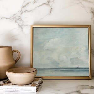 May include: A framed painting of a seascape with a light blue sky and white clouds. The sea is a deep blue and there is a small sailboat in the distance.