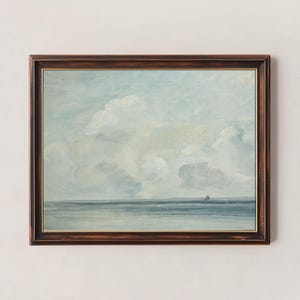 May include: A framed painting of a seascape with a light blue sky and white clouds. The sea is a dark blue and there is a small sailboat in the distance.