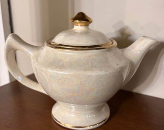 Tetera vintage de porcelana opalina iridiscente con brillo nacarado y ribete de oro de 22 quilates garantizado.