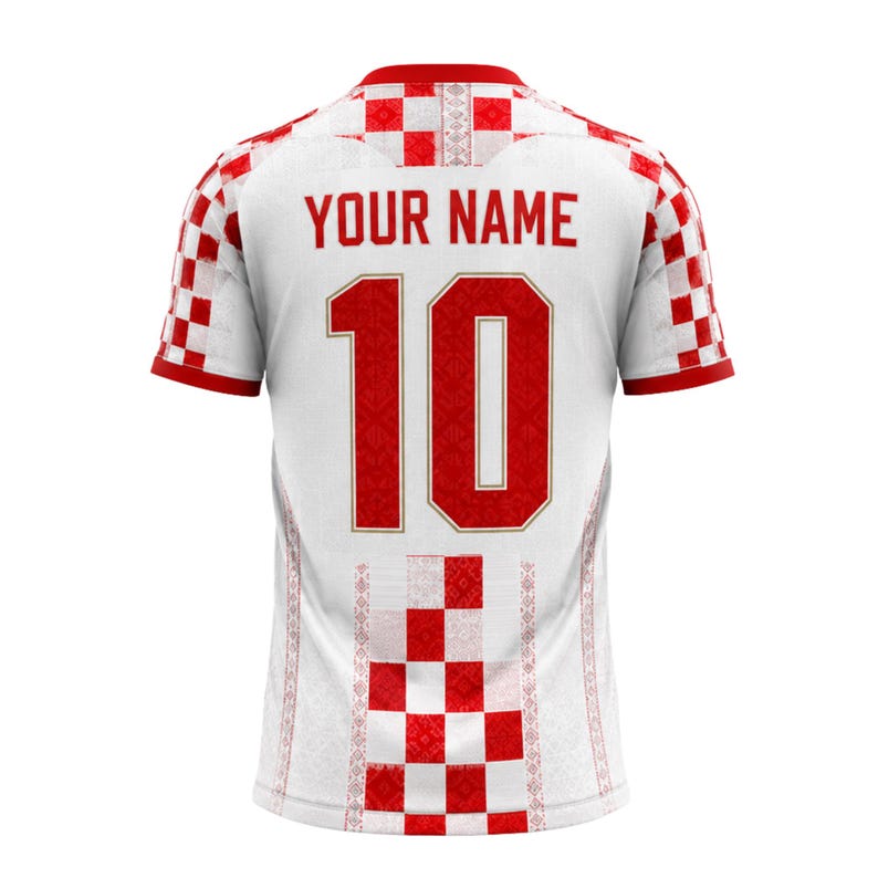 Pu&ograve; includere: Maglia da calcio bianca con dettagli rossi, con il numero 10 in rosso e la scritta "YOUR NAME" sopra. La maglia presenta un motivo a scacchi sulle maniche e sulla parte inferiore della schiena, con un design decorativo sui lati.